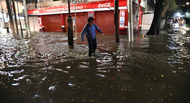 Persona caminando entre calles inundadas tras fuerte lluvia en zona urbana