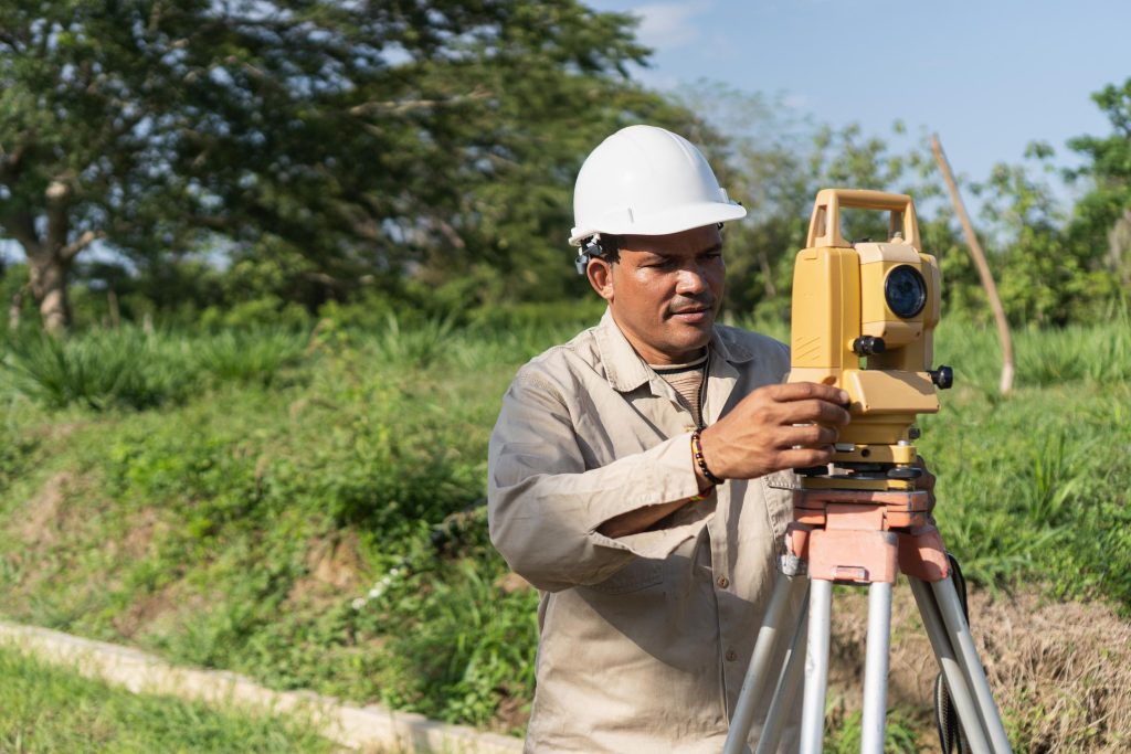 Ingeniero realizando levantamiento topográfico con estación total en terreno sin desarrollar